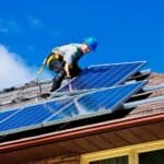 operaio sul tetto che fa manutenzione sui pannelli solari
